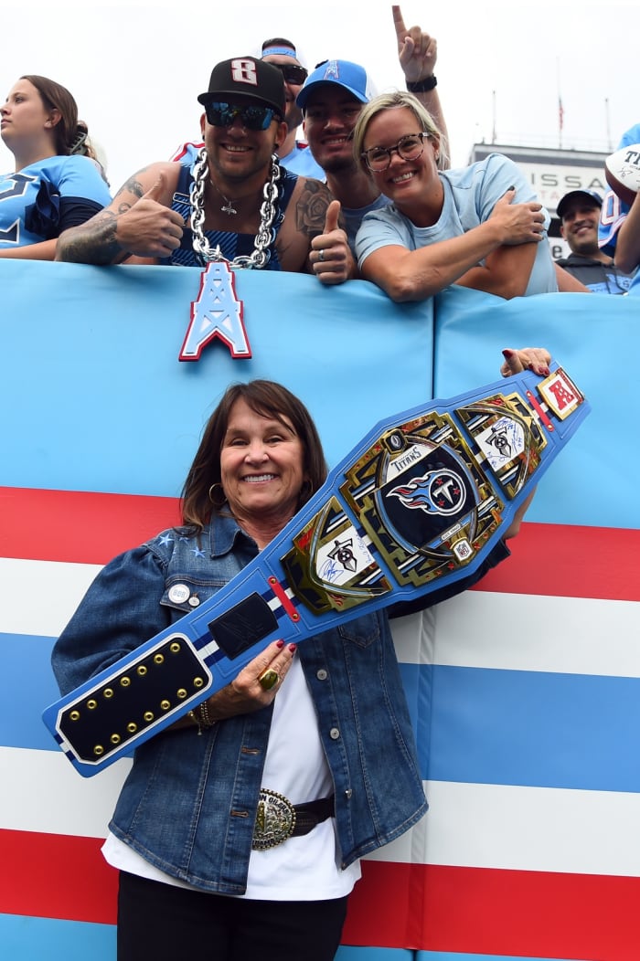 Tennessee Titans owner Amy Adams Strunk poses with a wrestling belt and fans before the game against the Atlanta Falcons at Nissan Stadium.
